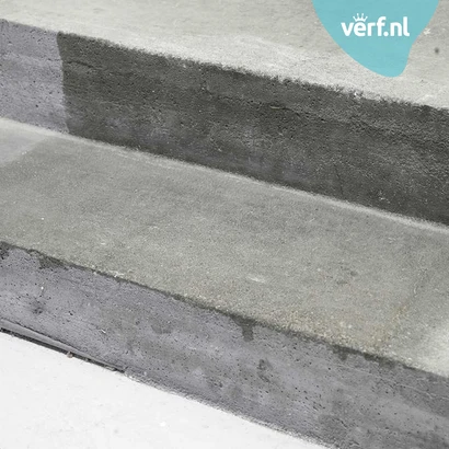 Betonnen trap met een duidelijk verschil tussen het onbehandelde en behandelde oppervlak. De rechterzijde is donkerder en verzadigd door het aanbrengen van Jotun Trestjerner Betongolje. Rechtsboven is het logo van Verf.nl zichtbaar.