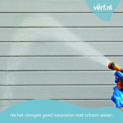 Gevel wordt afgespoeld met schoon water na reiniging met Jotun Kraftvask, hand met tuinslang zichtbaar.