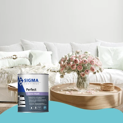Een lichte en frisse woonkamer met een witte bank en zachte mintgroene kussens. Op de houten salontafel staat een grote glazen vaas gevuld met roze ranonkels. Op de voorgrond staat een blik Sigma Coatings Perfect Semi-Matt muurverf. De onderzijde van de a