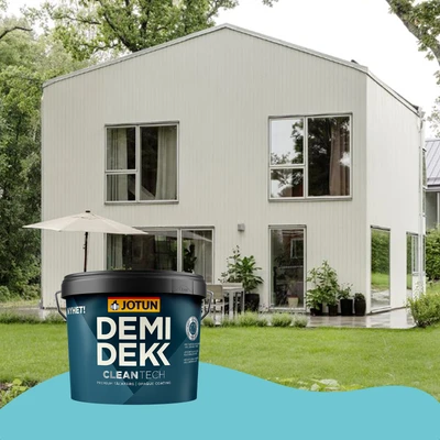 Een modern wit houten huis met grote ramen, geschilderd met Jotun Demidekk CleanTech. Op de voorgrond staat een grote emmer van deze verf op een blauwe ondergrond.