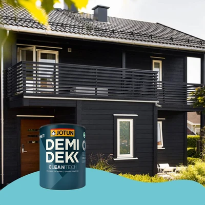 Een modern zwart houten huis met witte kozijnen, geschilderd met Jotun Demidekk CleanTech, waarvan een blik verf prominent op de voorgrond staat.