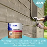 Persoon met handschoenen brengt met een kwast Sigma WoodProtect Gloss aan op houten schutting buiten, met een blik beits op de voorgrond.