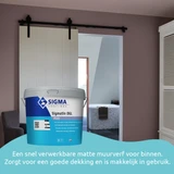Slaapkamer met een mat lila geschilderde muur en een schuifdeur die toegang geeft tot een moderne badkamer. Op de voorgrond staat een emmer Sigma Sigmatin DGL Matt muurverf. De tekst beschrijft het product als een snel verwerkbare matte muurverf voor binn