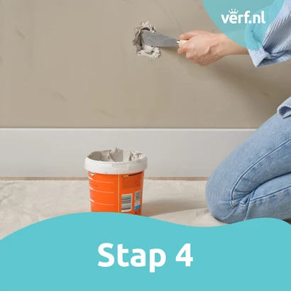 Stap 4: Gat vullen: Iemand brengt het vulmiddel aan in het gat met een plamuurmes, terwijl de pot Alabastine Grote Gaten Vuller open naast hen staat.