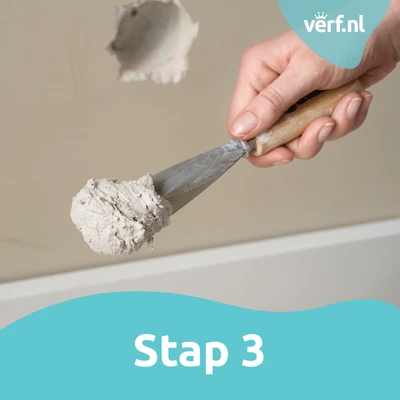 Stap 3: Vulmiddel aanbrengen: Een hand houdt een plamuurmes met een grote hoeveelheid vulmiddel, klaar om het op de muur aan te brengen.