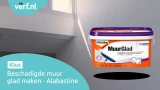 Een emmer Alabastine MuurGlad voor een beschadigde muur bij een trapgat, met invallend daglicht door een raam. Linksboven het Verf.nl-logo en linksonder de tekst: "Beschadigde muur glad maken – Alabastine."