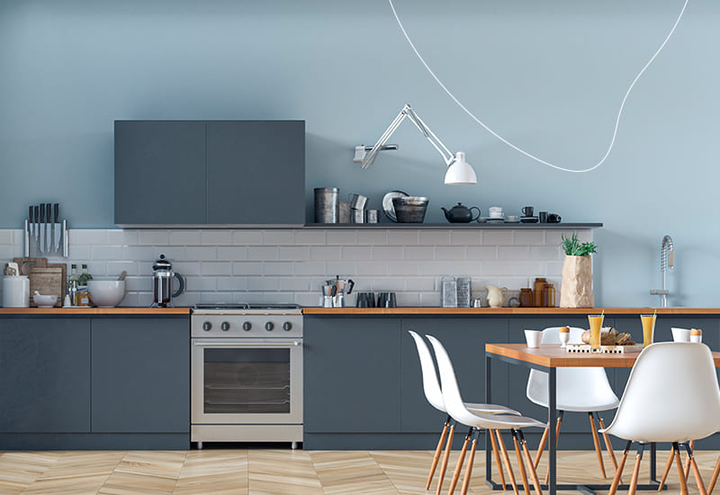 Een moderne groenblauwe keuken, met een lichtblauwe muur, een achterwand met witte tegels en een houten keukenblad.